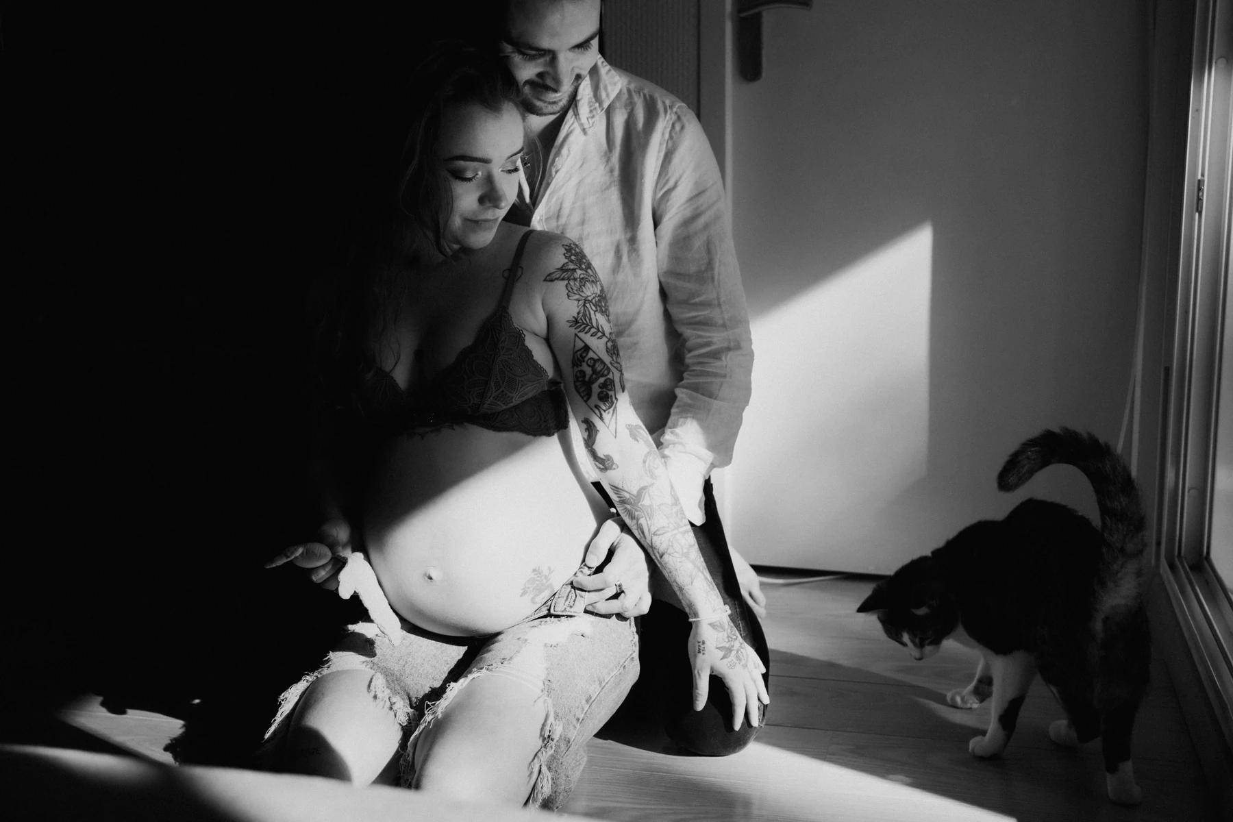 Photo grossesse artistique à domicile en noir et blanc avec lumière naturelle forte et chat