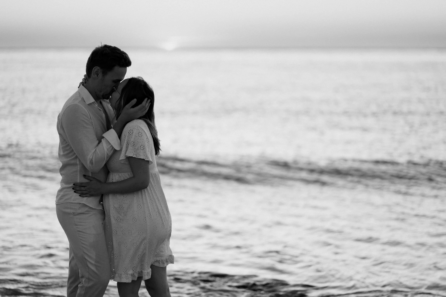 photo grossesse en noir et blanc d’un couple s’enlaçant au bord de l’eau au Pyla-sur-Mer