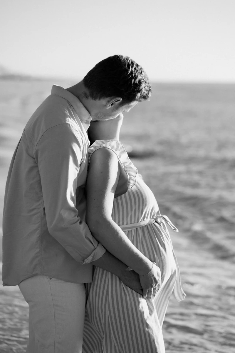 futur papa embrassant sa compagne enceinte lors d’une séance grossesse au Pyla-sur-Mer
