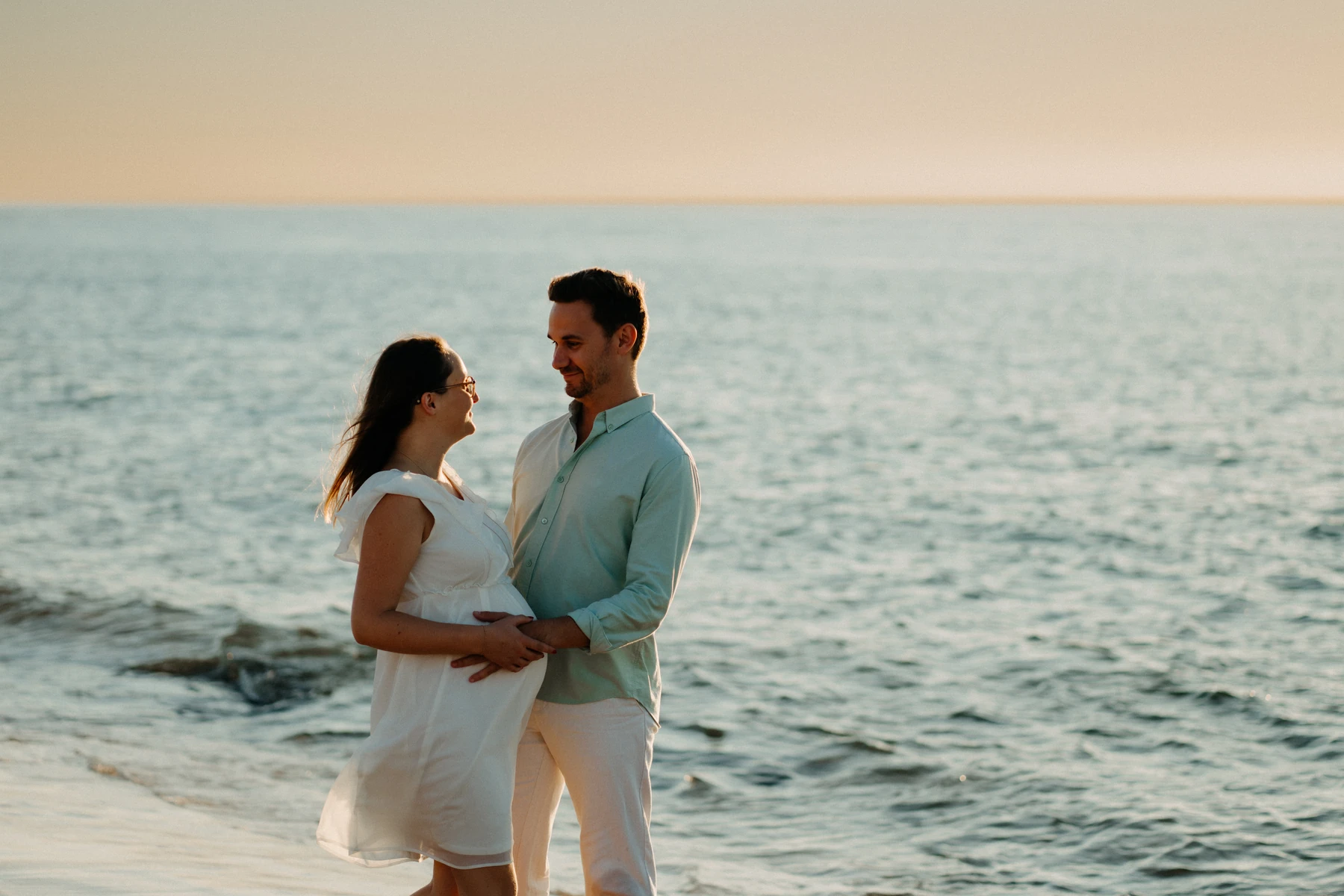 photo de grossesse sur la plage du Pyla, couple amoureux en blanc au bord de l’océan