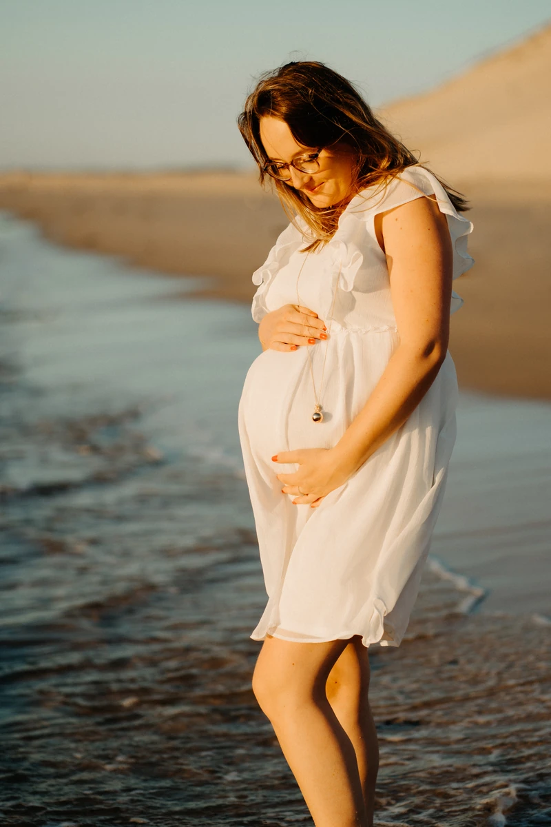 photo grossesse naturelle au coucher de soleil sur la plage du Petit Nice, future maman en robe blanche à Pyla-sur-Mer