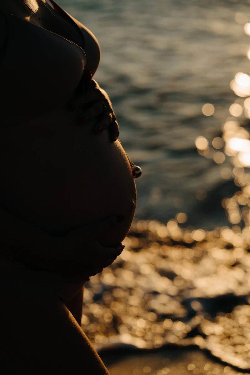 Ventre arrondi de future maman au coucher du soleil sur la plage du Petit Nice