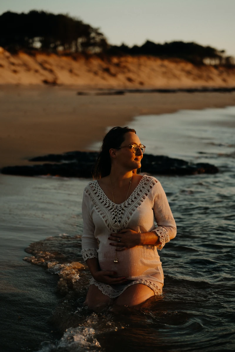 Future maman dans l’océan au coucher du soleil, lumière dorée sur la plage du Petit Nice à Pyla-sur-Mer