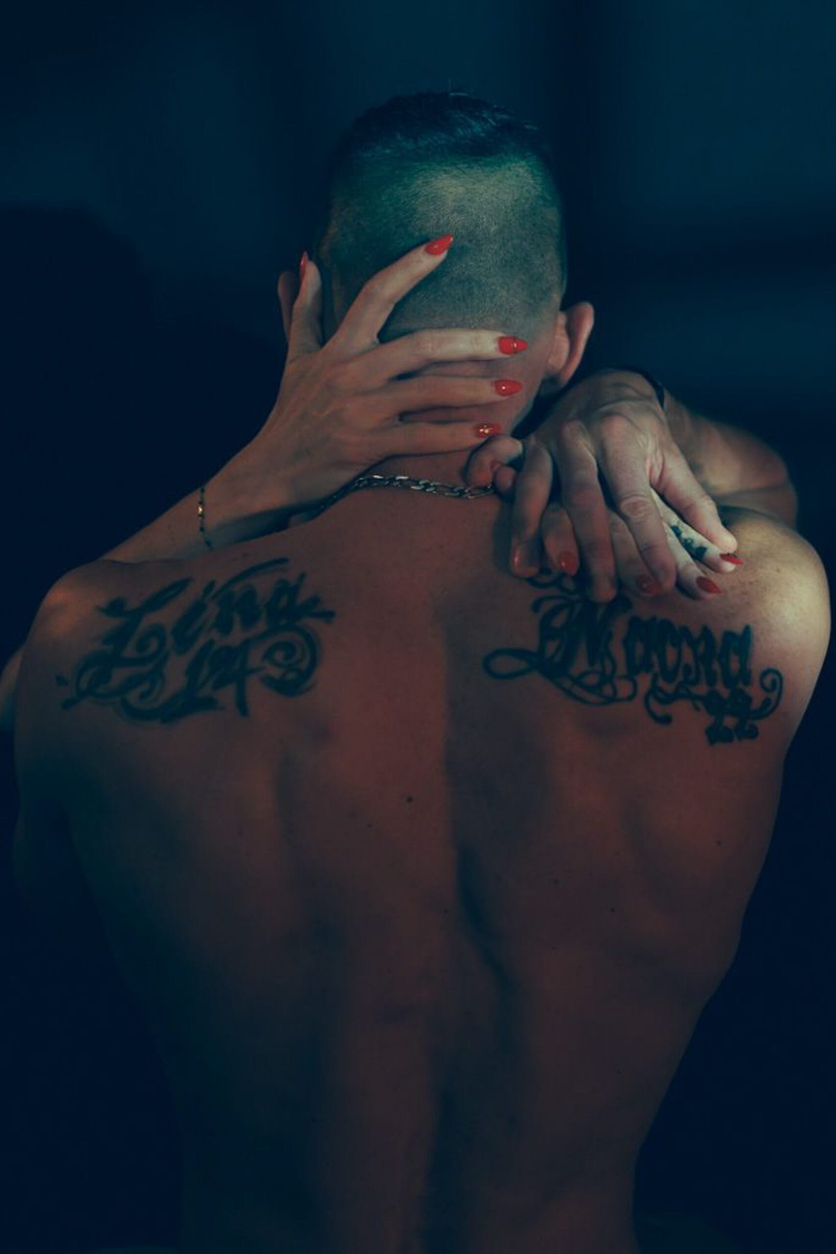 Photographie boudoir intime, couple enlacé vu de dos, lumière tamisée et ambiance sensuelle.